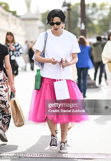 Guest is seen wearing a white t-shirt, pink tule skirt and Converse sneakers with black sunglasses outside the Dior show during the Womenswear...