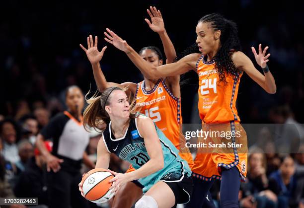 Sabrina Ionescu of the New York Liberty dribbles against Tiffany Hayes and DeWanna Bonner of the Connecticut Sun during the first half of Game Two of...