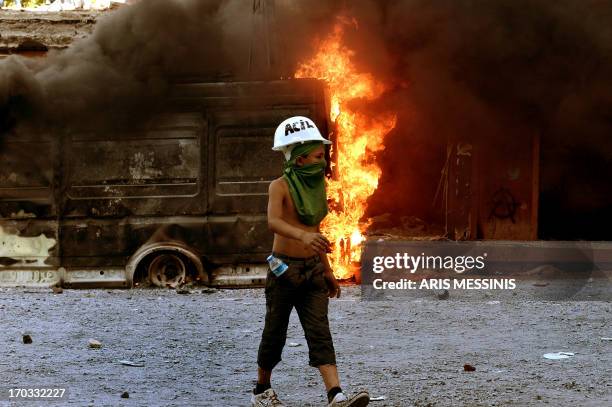 Young protester passes a burning vehicle at Taksim square in Istanbul on June 11, 2013. Riot police fired tear gas and rubber bullets to clear...