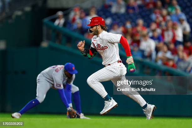 Bryce Harper of the Philadelphia Phillies runs to second base as second baseman Ronny Mauricio of the New York Mets fields a ground ball during a...