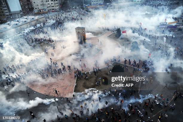 People run away as Turkish riot policemen fire tear gas on Taksim square on June 11, 2013. Turkish police fired massive volleys of tear gas and jets...