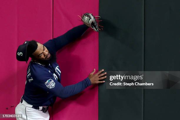 Teoscar Hernandez of the Seattle Mariners crashes into the outfield wall after making a leaping catch for an out against the Houston Astros during...