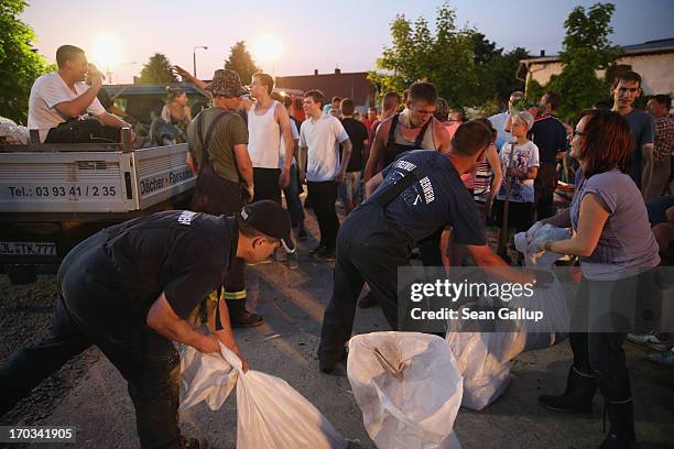 Volunteers load sandbags onto a truck to deliver them to local homes against the spreading floodwaters of the Elbe river on June 11, 2013 in Wust,...