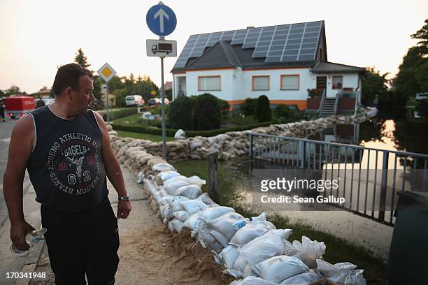 Local resident looks at water encroaching upon his home as sandbags stacked by volunteers stand in rows to protect it from the spreading floodwaters...
