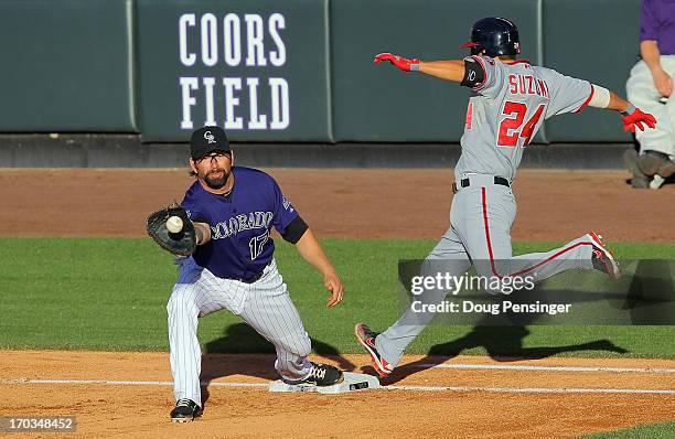 Kurt Suzuki of the Washington Nationals is safe at first base as first baseman Todd Helton of the Colorado Rockies takes the throw from third baseman...