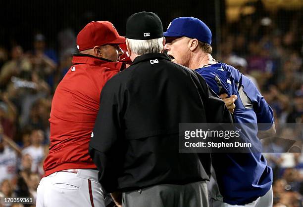 Batting coach Mark McGwire of the Los Angeles Dodgers has words with manager Kirk Gibson of the Arizona Diamondbacks as first base umpire Brian...