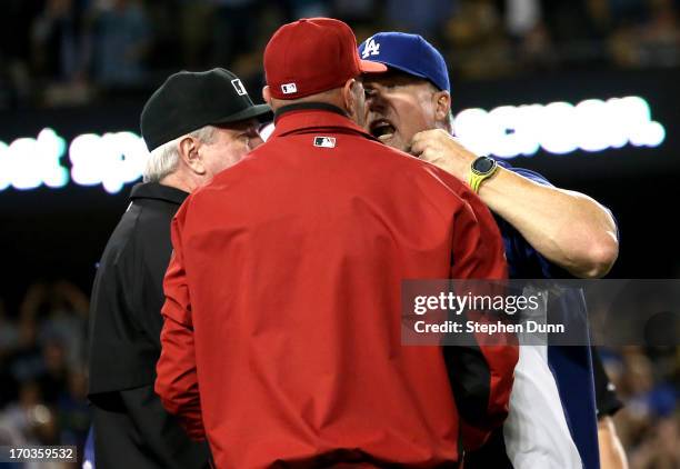 Batting coach Mark McGwire of the Los Angeles Dodgers has words with manager Kirk Gibson of the Arizona Diamondbacks as first base umpire Brian...