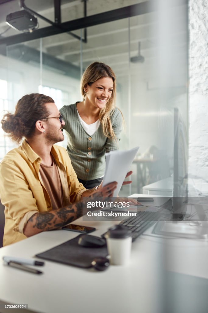 Happy programmers working on PC and reports in the office.