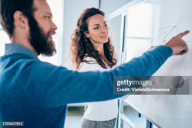 young colleagues drawing a business plan on whiteboard in the office. - business plan covid stock pictures, royalty-free photos & images