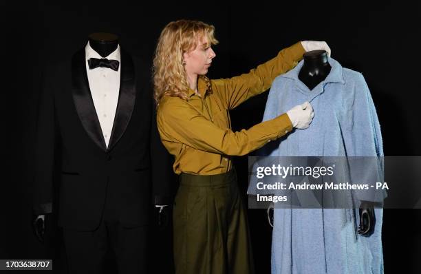 Propstore employee adjusts Honey Ryder's bathrobe from the 1962 James Bond film 'Dr No' which is alongside Daniel Craig's tuxedo from the 2021 James...