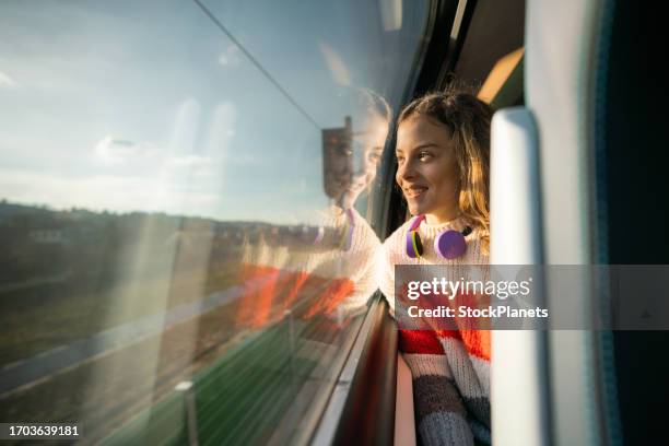 ein glückliches kleines mädchen mit lockigem haar schaut durch das fenster, während es mit dem zug fährt - europe travel stock-fotos und bilder
