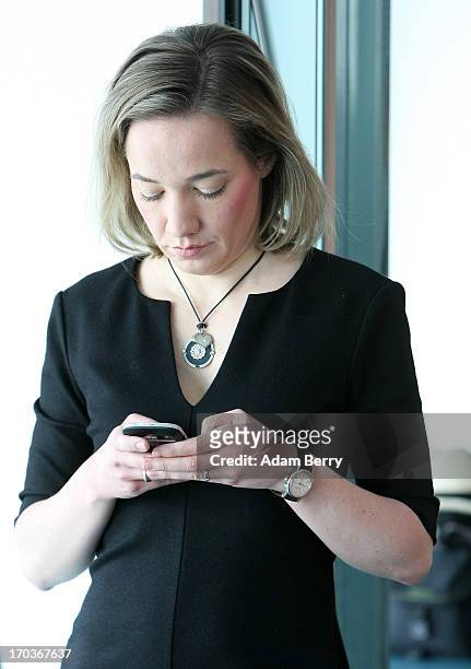 German Family Minister Kristina Schroeder checks her mobile phone as she arrives for the weekly German federal Cabinet meeting on June 12, 2013 in...