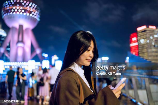 businesswoman using mobile phone while standing under oriental pearl tower in shanghai, china - china oriental stock pictures, royalty-free photos & images
