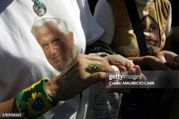 Catholic believer wearing a Pope Benedict XVI T-shirt receives an host as she waits to spend the night at the National Sanctuary of Aparecida, in...