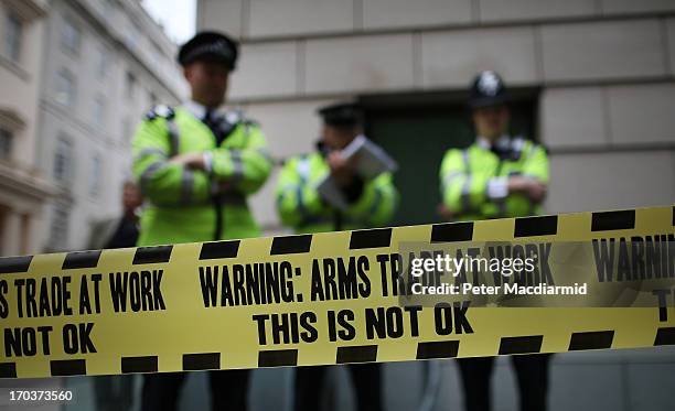 Police stand behind some anti-arms trade cordon tape during protests outside arms manufacturer BAe Systems on June 12, 2013 in London, England....