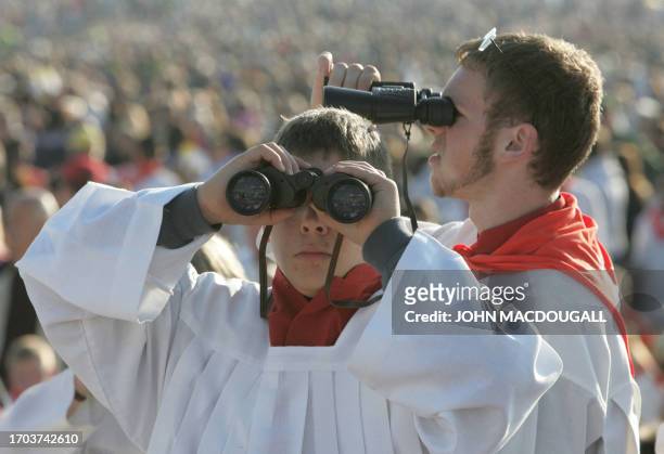 Catholic devotees use binoculars to survey the crowd, as they wait for Pope Benedict XVI to hold a mass in a field near Regensburg 12 September 2006....