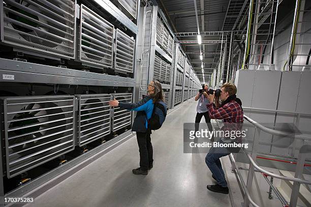 Visitor poses for photographers next to cooling fans operating in Facebook Inc.'s new data storage center near the Arctic Circle in Lulea, Sweden, on...