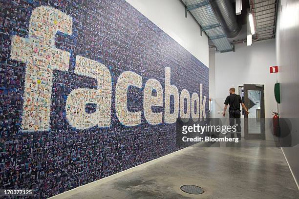 An employee passes a logo made from a collection of photographs on a wall inside Facebook Inc.'s new data storage center near the Arctic Circle in...