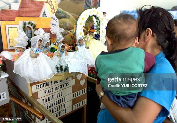 Woman holding her daughter looks on the altar to the Saints of Innocent Children during a traditional religious celebration in Anitguo Cuscatlan, El...