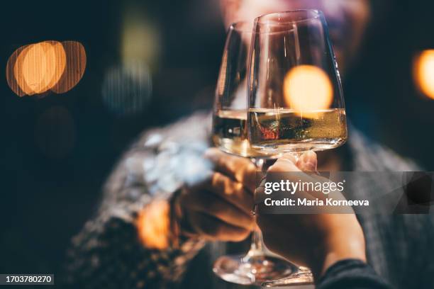 toasting with white wine on a romantic date night. couple drinking white wine and toasting. - mesa para dos fotografías e imágenes de stock