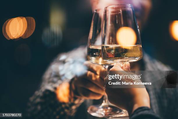 toasting with white wine on a romantic date night. couple drinking white wine and toasting. - table for two stock pictures, royalty-free photos & images