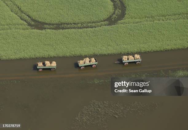 In this aerial view three farm wagons loaded with sacks stand in floodwaters from the Elbe river on June 12, 2013 near Fischbeck, Germany. The...