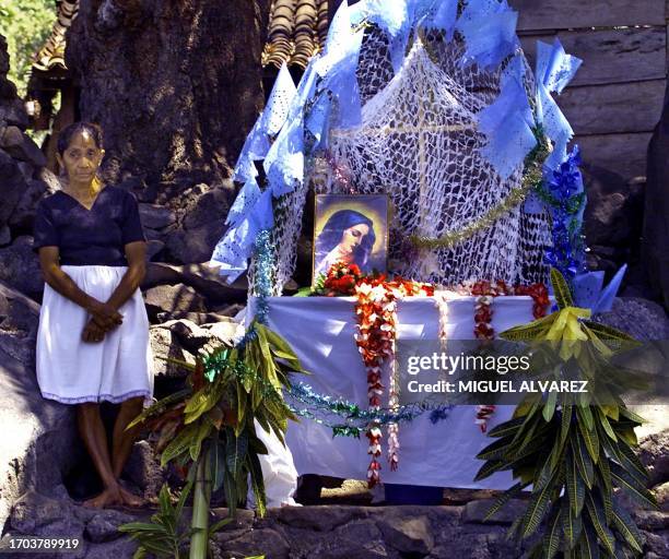 Woman waits next to an altar adorned with fishing nets, flowers and the image of the Virgin Mary, the arrival of the small boats that accompany the...