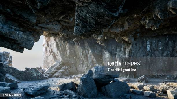 the warm daylight gently brightens the stone floor within the rocky cave. - rotsformatie stockfoto's en -beelden