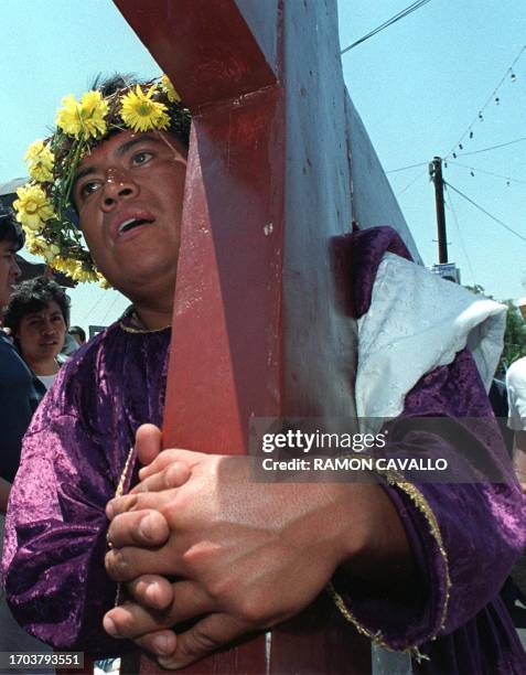 Catholic carries a cross during a representation of the passion of Christ during Saint's Week, in Mexico City, 21 April 2000. Un catolico carga una...