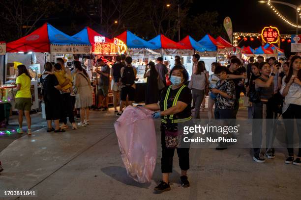 Cleaning worker with a plastic bag at a pop up night market in wan chai promenade on October 2, 2023 in Hong Kong, China. The Night Market in Wan...