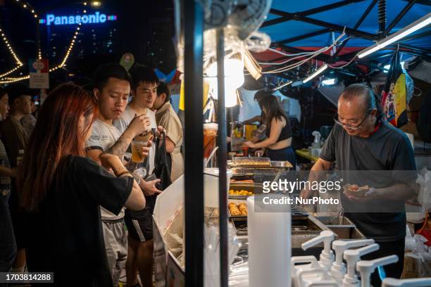 People buying food from a vendor at a pop up night market in wan chai promenade on October 2, 2023 in Hong Kong, China. The Night Market in Wan Chai...