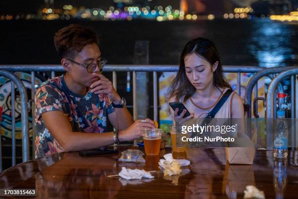 Two people eating at a table at a pop up night market in wan chai promenade on October 2, 2023 in Hong Kong, China. The Night Market in Wan Chai...