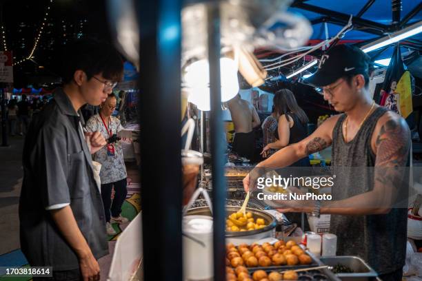Man buying food from a vendor pop up night market in wan chai promenade on October 2, 2023 in Hong Kong, China. The Night Market in Wan Chai...