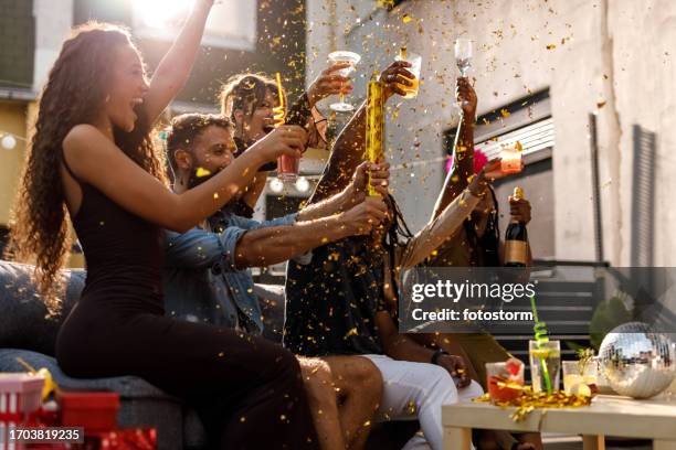 exploding gold colored confetti during a celebratory party on the balcony - party popper stockfoto's en -beelden