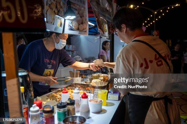 Women buying food from a vendor pop up night market in wan chai promenade on October 2, 2023 in Hong Kong, China. The Night Market in Wan Chai...