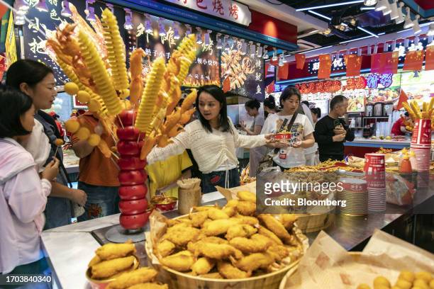 Customers pass a food stall in Shanghai, China, on Tuesday, Oct. 3, 2023. China's Golden Week got off to a promising start as tourist trips and...