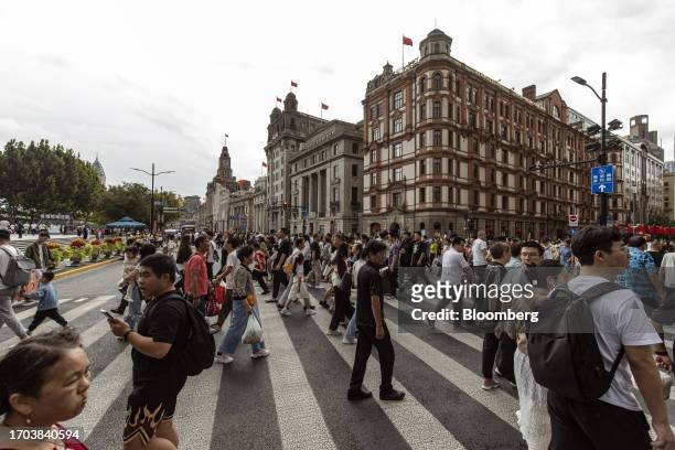 Pedestrians cross a road near the Bund in Shanghai, China, on Tuesday, Oct. 3, 2023. China's Golden Week got off to a promising start as tourist...