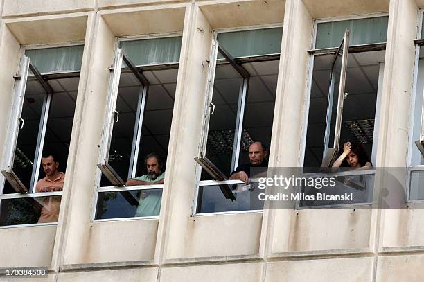 Workers look out from windows as they occupy the headquarters of the Greek public broadcaster ERT in Athens, on June 12, 2013 in Athens, Greece....