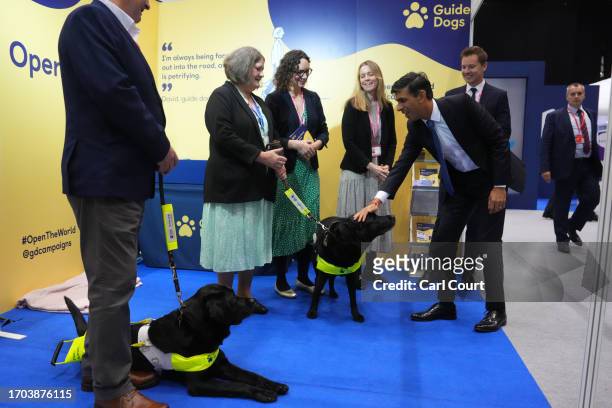 British Prime Minister Rishi Sunak greets a guide dog as he tours the Exhibitor's Hall on Day 3 of the Conservative Party Conference on October 3,...