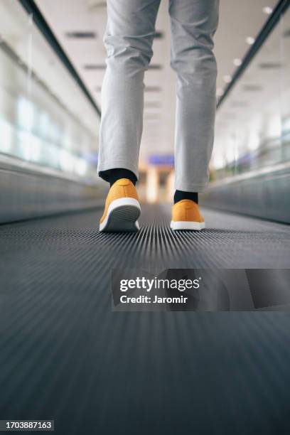 legs of well-dressed man on moving walkway - moving walkway airport stock pictures, royalty-free photos & images