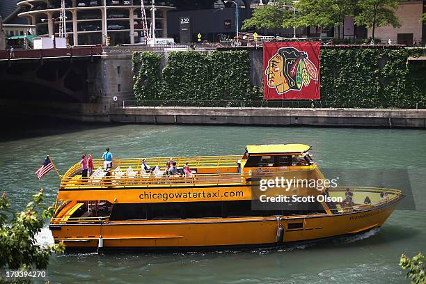 Water taxi passes by a Chicago Blackhawks' banner on the Chicago River in the Loop on June 12, 2013 in Chicago, Illinois. The Chicago Blackhawks will...