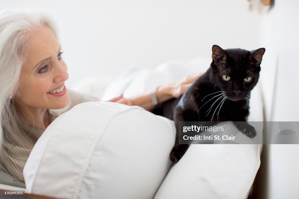 Smiling mature woman at home, with cat on sofa