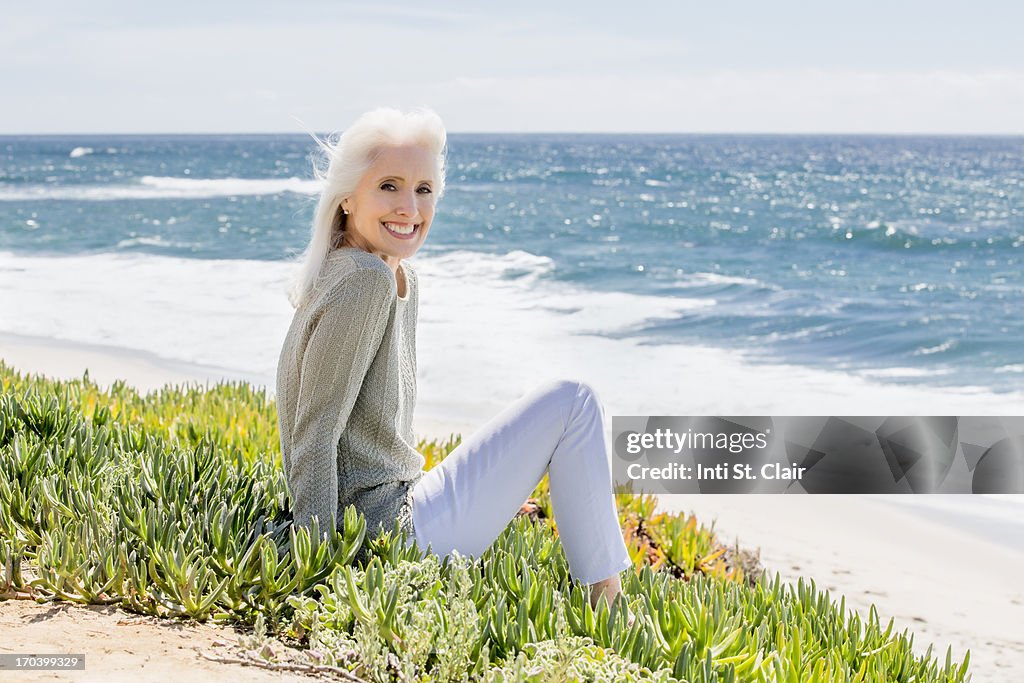 Mature woman at sitting at the beach, smiling