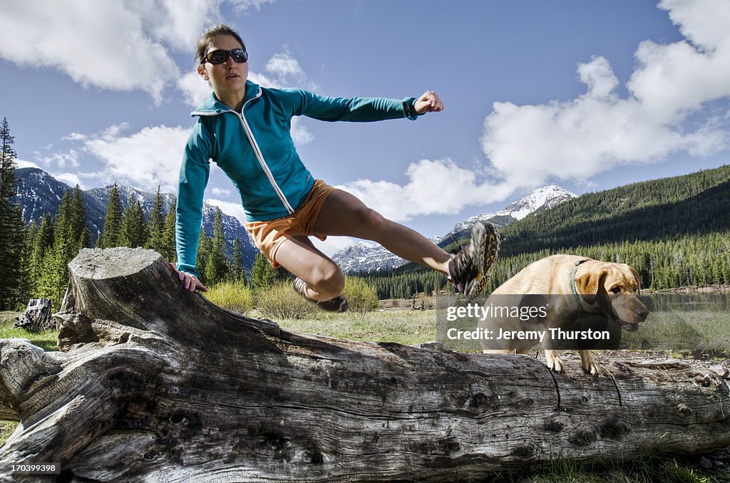 Young woman and her dog vault a log