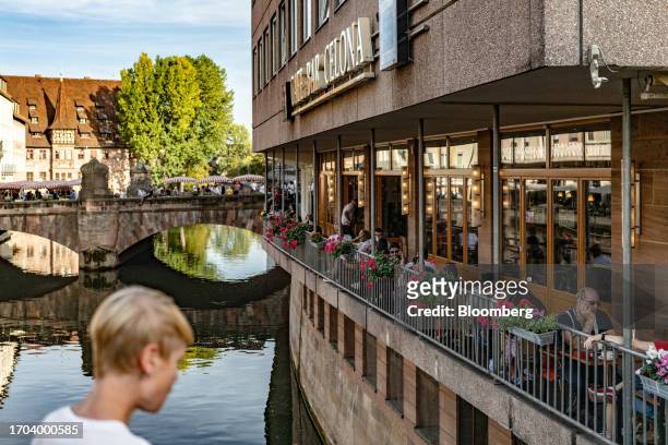 Customers sit at terrace tables on the bank of the River Pegnitz in Nuremberg, Germany, on Monday, Oct. 2, 2023. German inflation plunged to its...