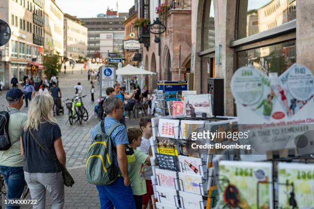 Tourists look at postcards for sale in Nuremberg, Germany, on Monday, Oct. 2, 2023. German inflation plunged to its lowest level in two years after...
