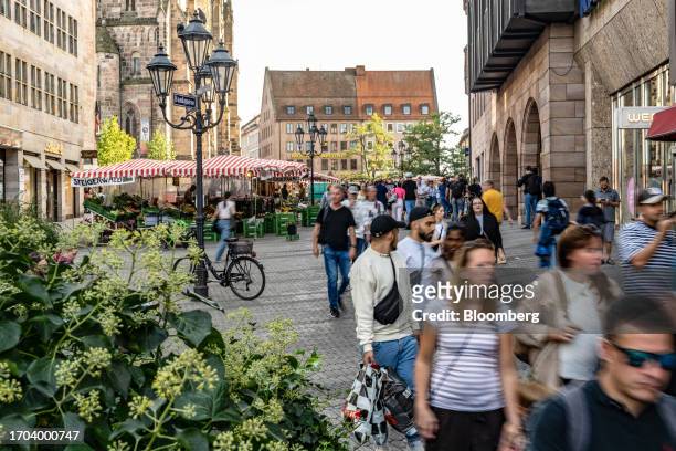 Shoppers pass market stalls in Nuremberg, Germany, on Monday, Oct. 2, 2023. German inflation plunged to its lowest level in two years after the...