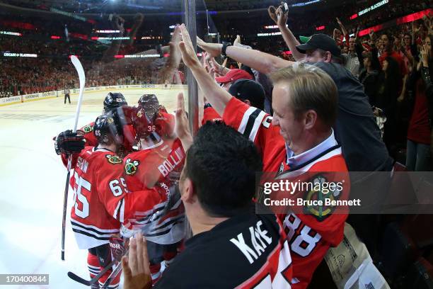 Fans cheer as Dave Bolland of the Chicago Blackhawks celebrates with teammates after Bolland scored a goal in the third period against the Boston...