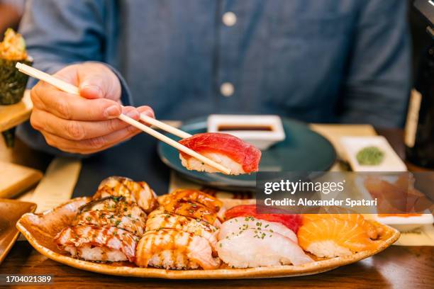 man eating tuna nigiri sushi at the restaurant, close-up - eetstokje stockfoto's en -beelden