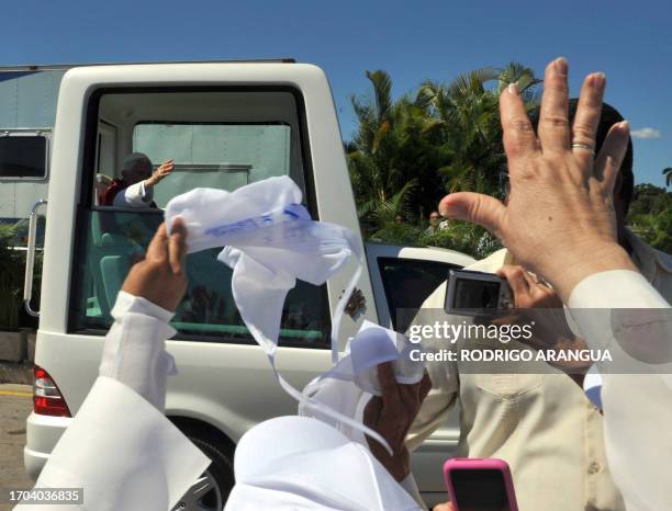 Pope Benedict XVI greets believers from the popemobile after celebrating a mass at Revolution Square in Havana, on March 28, 2012. Benedict XVI was...